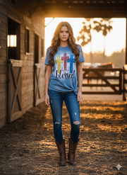 Woman wearing a 'blessed' t-shirt with colorful crosses in a barn setting.